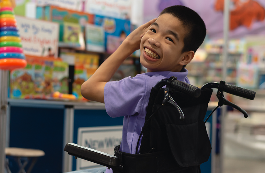 a young boy in a wheelchair smiles at camera