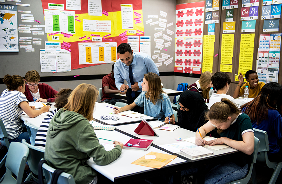 a wide shot of a busy classroom with older students and the instructor in the middle