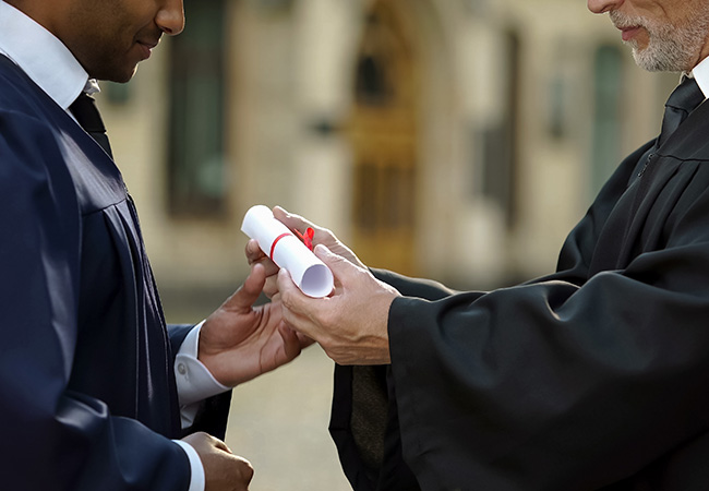 2 men in graduation regalla hold a degree