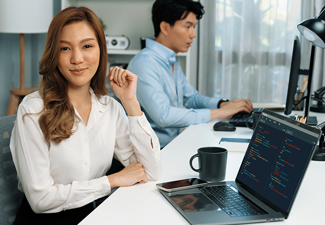 a woman with her laptop smiles directly at camera