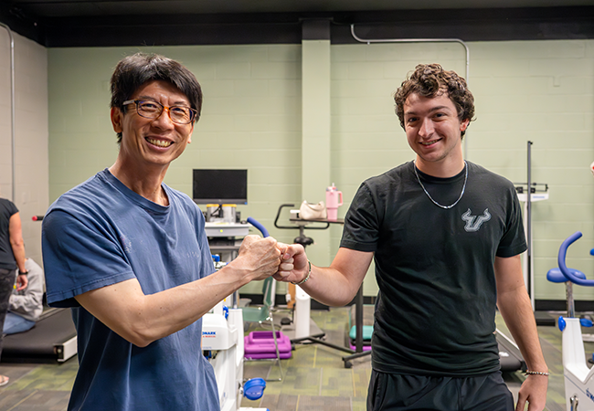 a usf exercise sceince student and patient fist bump and smile at camera