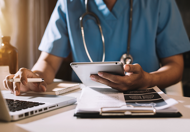 close up of a nurse or doctor's hands holding an ipad while working at their desk