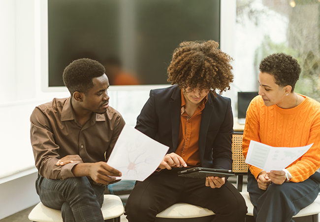 3 students sit together and do school work