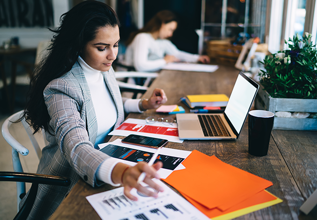 a professional woman works on an ipad with a busy desk
