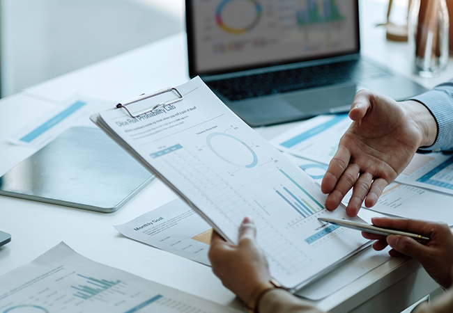 close up of hands looking down and analyzing a paper with charts and graphs