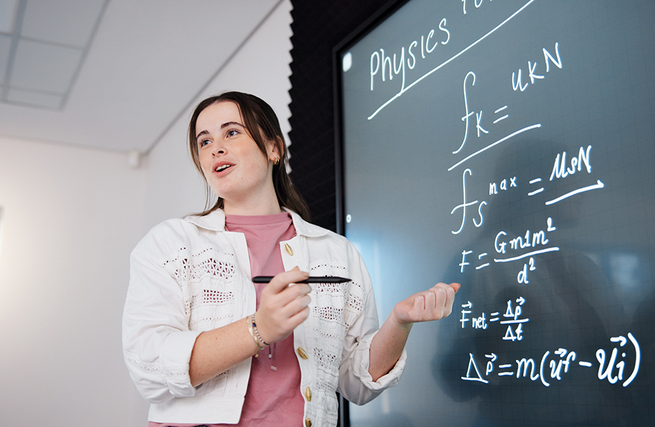 person doing a physics equation on a smart board