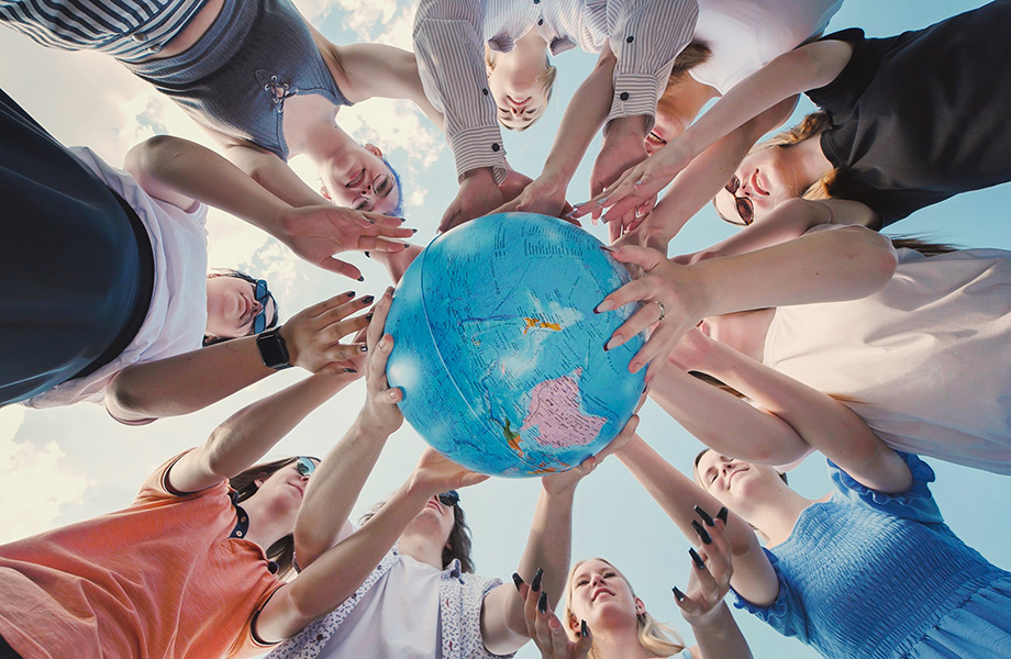 a group of studnets in a cricle with the camera view up with them holding a globe