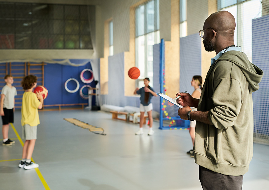 A coach stands in front of children coaching them
