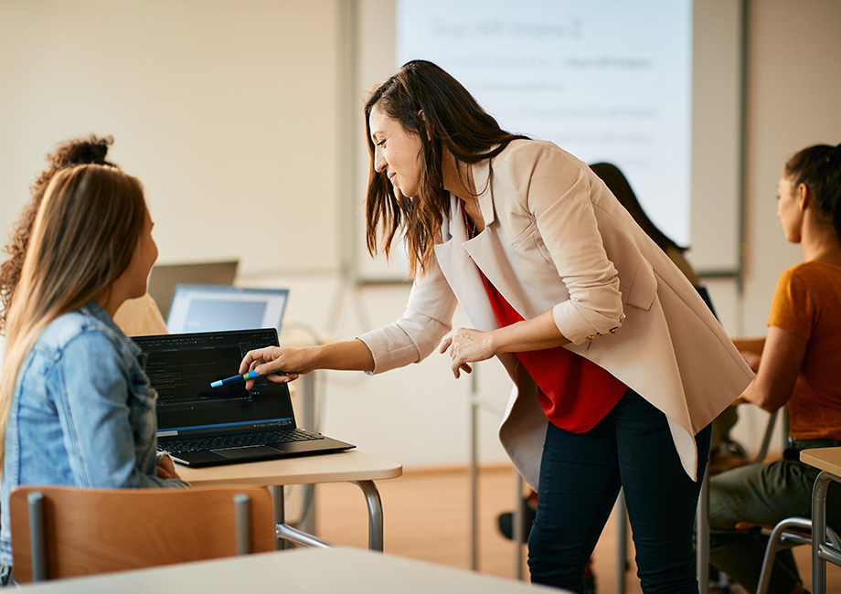 a woman teahcer helps a high school girl with a computer