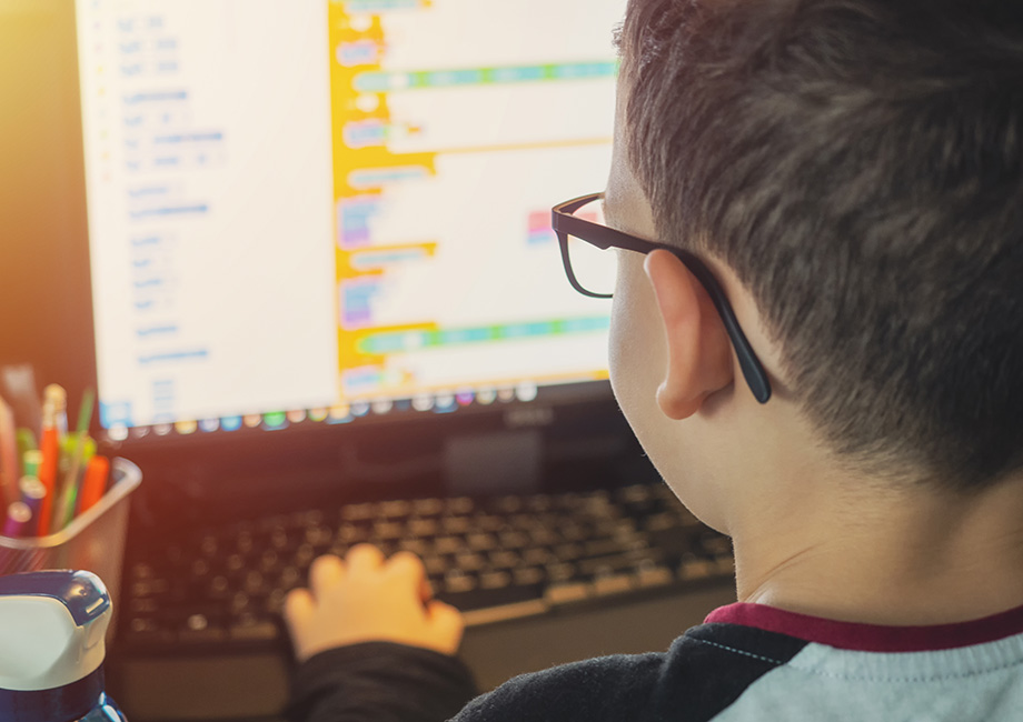 a young student with glasses looking close up at a computer screen