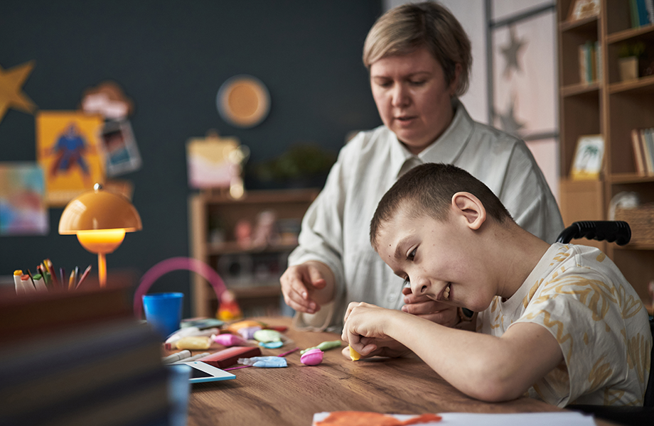 a woman sits and plays with an exceptional student