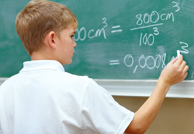 a young boy does a math problem on a chalkboard