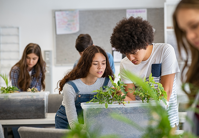 2 students in science class working on something with plants