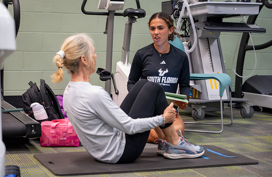ESK student works with woman seated on exercise mat