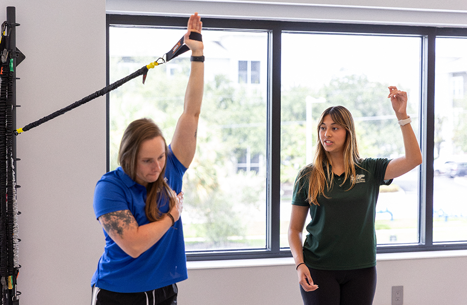 USF staff member assists client with exercise equipment