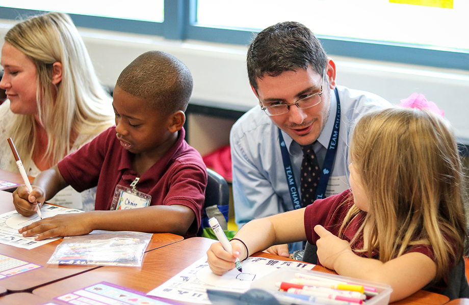 male teacher working with children in classroom