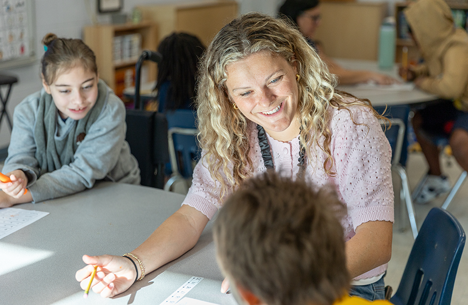 woman works with young students in classroom