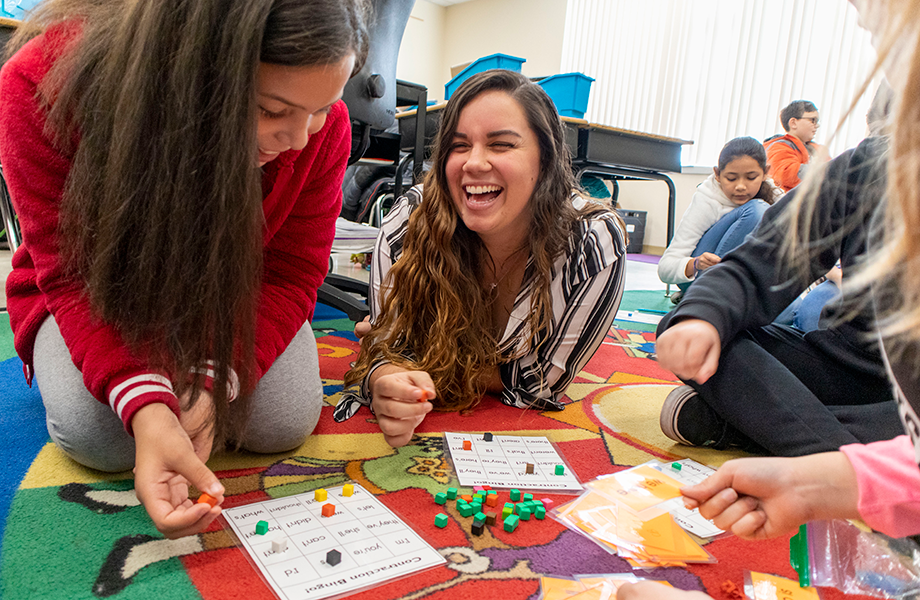 teacher laughs with young students in classroom