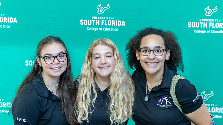 Three students in front of COEDU backdrop