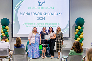 ESE faculty presenting a certificate to a student and mentor teacher