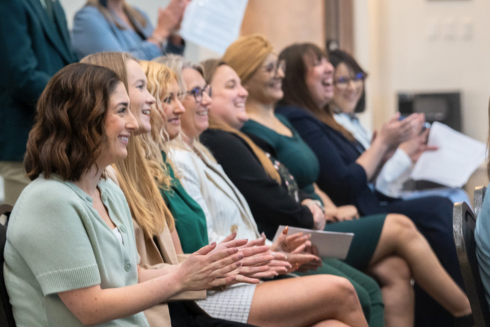People sitting in a row clapping and smiling 