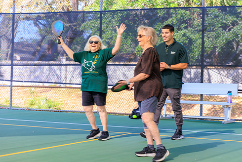 Two women learning to play pickleball with Education student