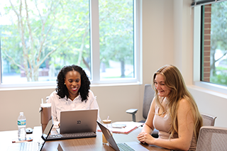 two mentors at table with laptops