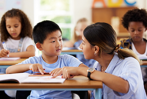 Teacher talking to young student in classroom