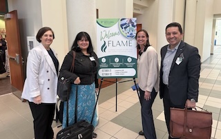 four participants smiling by the flame sign