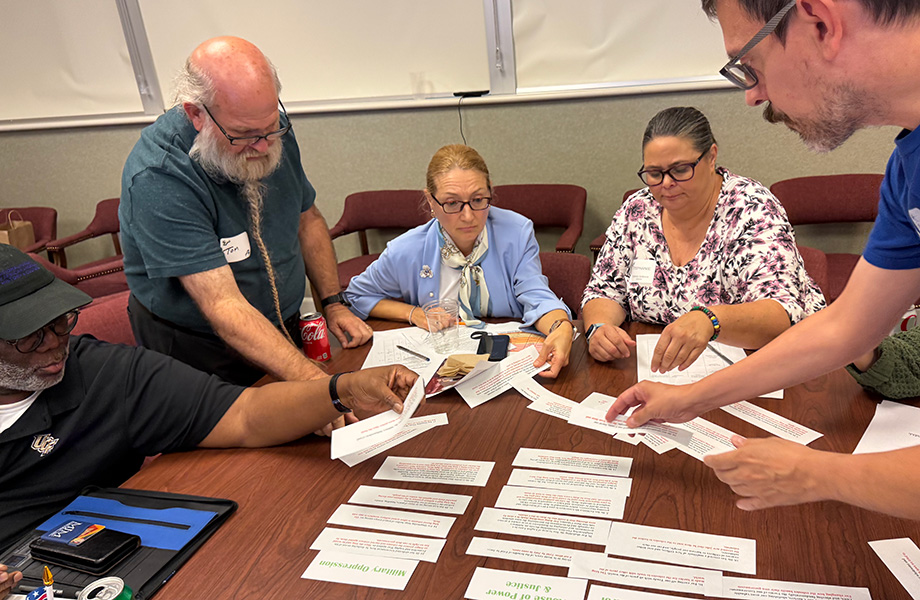 a group of workshop participants sit at table exhanging small pieces of paper during activity
