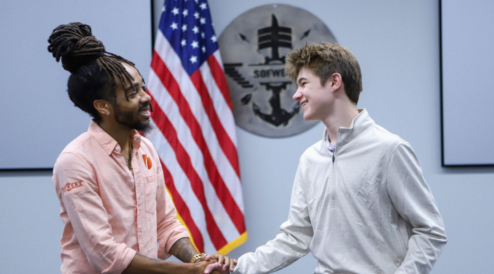 Two indivduals smiling and shaking hands