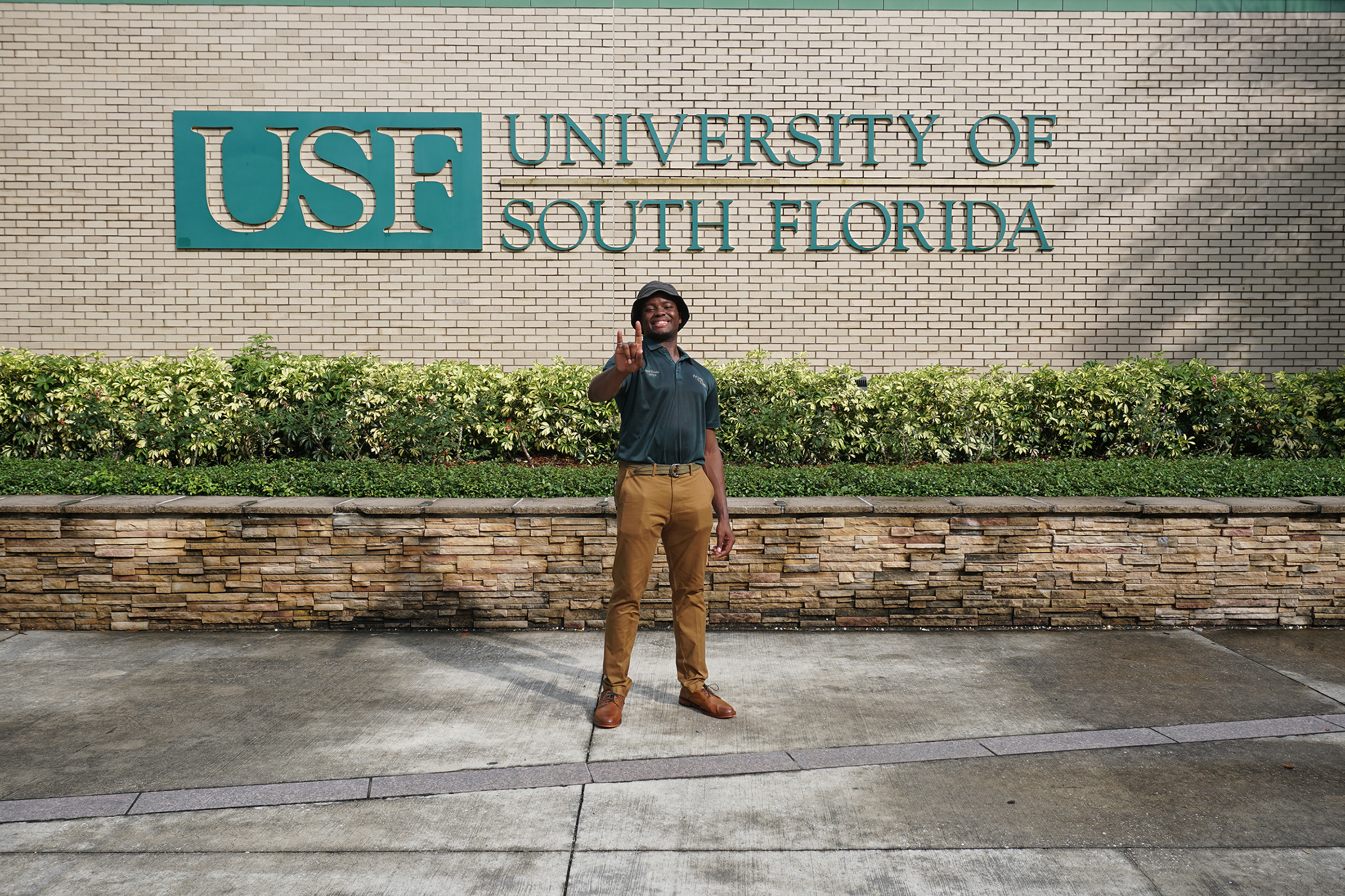 Ossie Douglas in front of the USF sign by the USF Bookstore