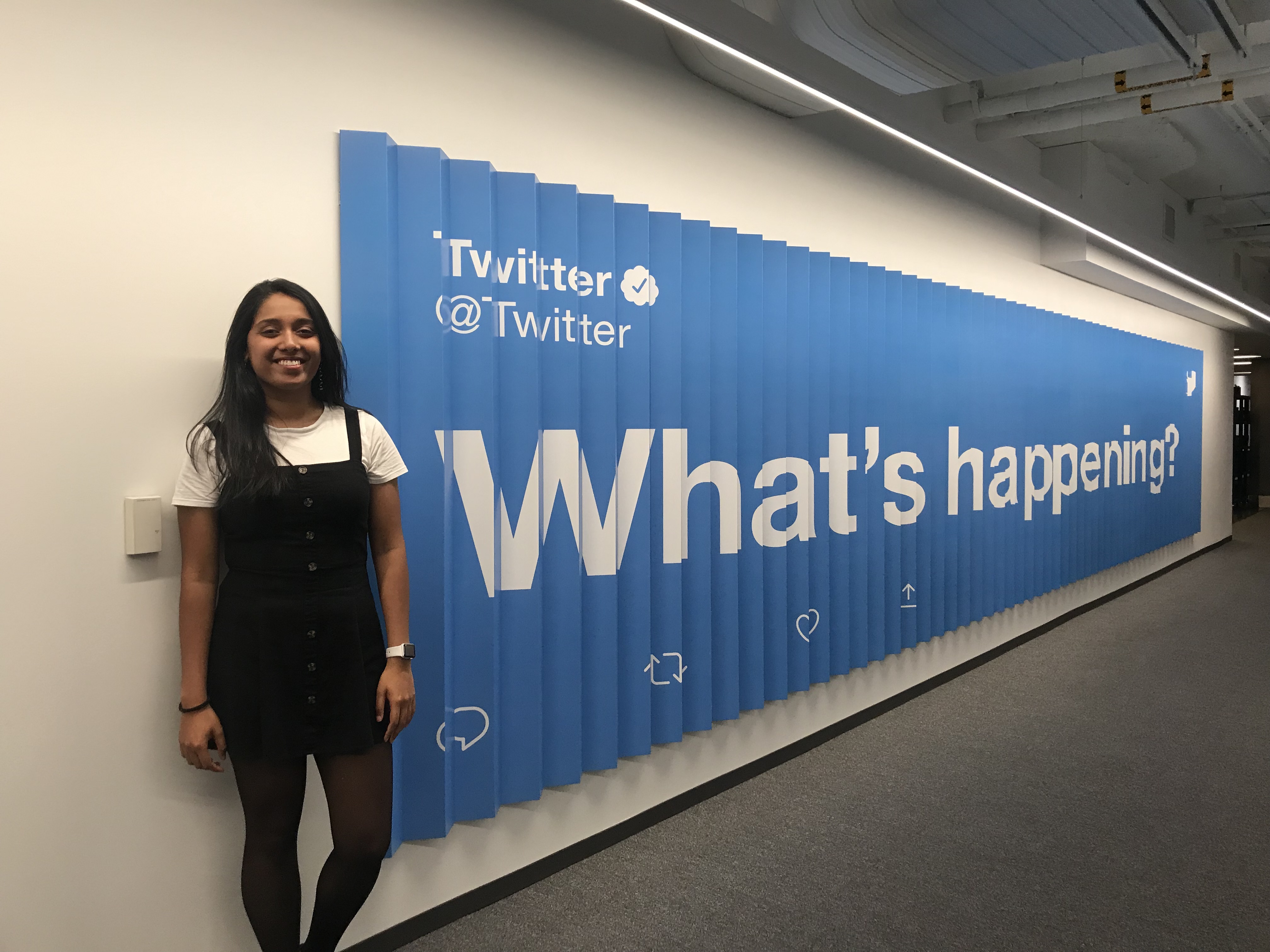 Blanche Pinto next to a sign at Twitter HQ