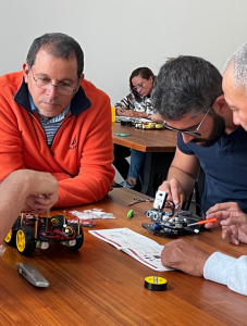 Participants collaborate on assembling robotics kits during a hands-on workshop, focusing on intricate components and instructions. The scene captures teamwork and engagement in a STEM-focused activity.