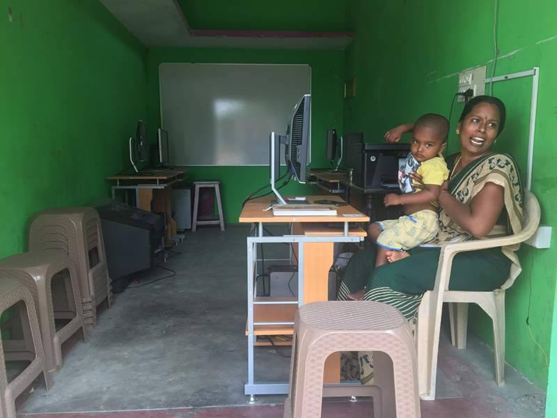 An Indian woman sits at a computer with a child.