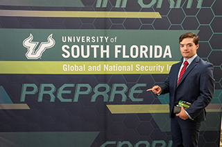 A student standing in front of the GNSI banner at the 2026 USF Undergraduate Strategy Competition
