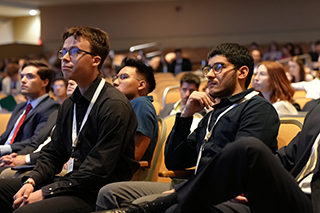 Group of students listening intently to a speaker in an auditorium.