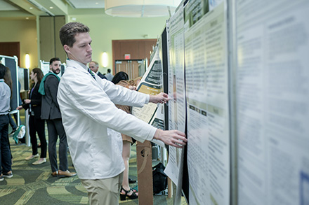 A student sets up his poster at USF Health Research Day.
