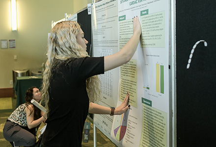 A student sets up her poster at USF Health Research Day.