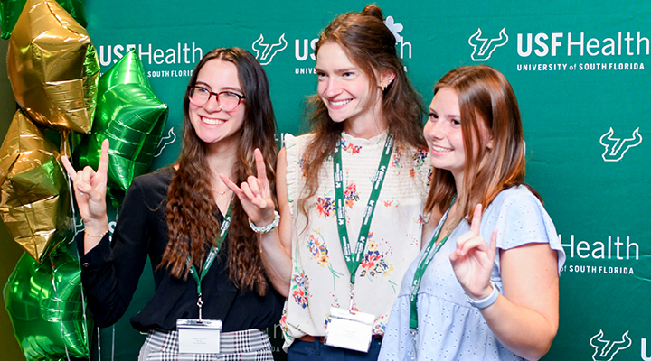 Three students with the Go Bulls sign