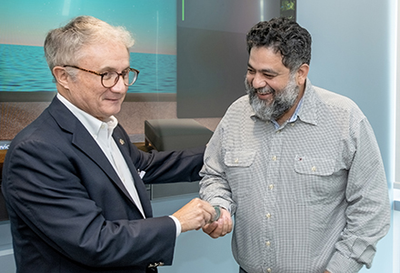 two men with a culture coin in a small conference room