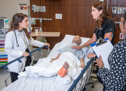 Melissa Milner (center), director of clinical simulation at USF CAMLS, speaks to students during a health care simulation exercise
