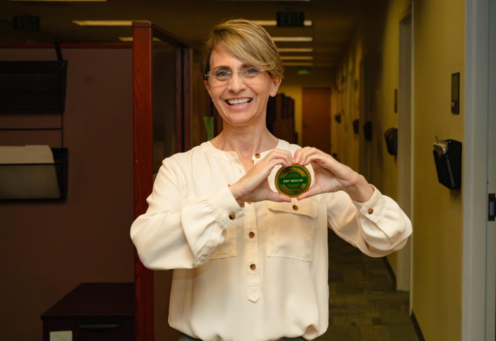 Jennifer Newcomb holding a USF Health culture coin
