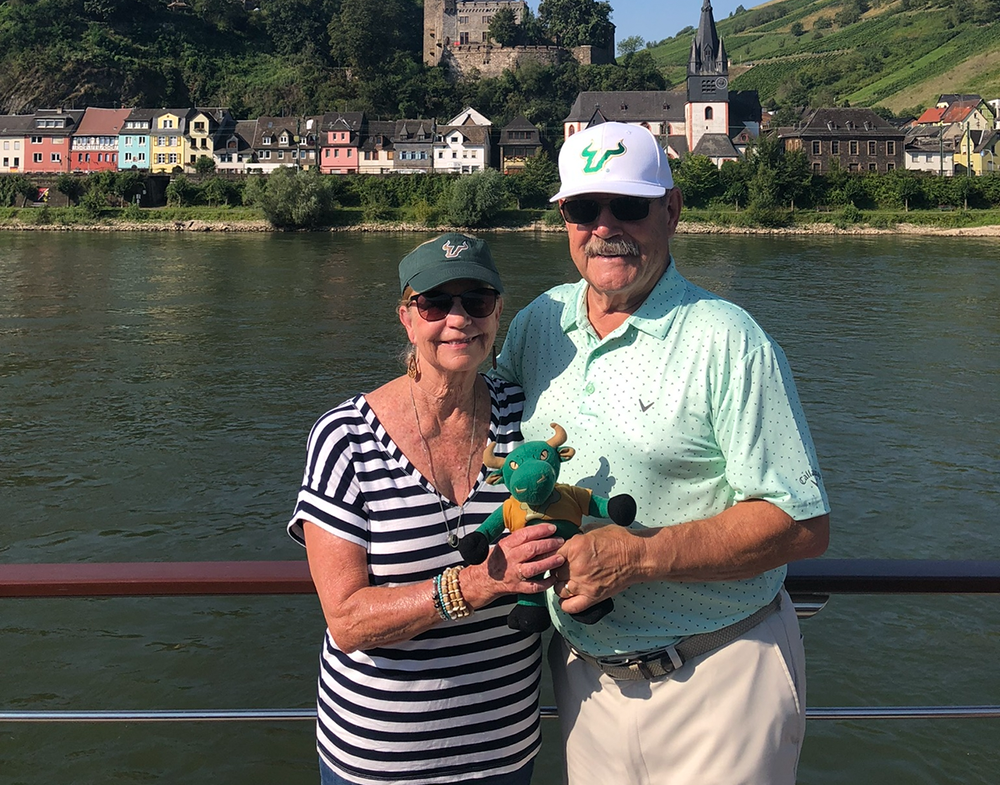 A couple stand on a boat deck with a plush bull