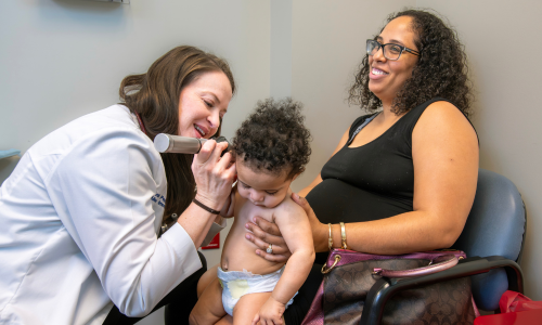 Dr. Pepper checking the ear of a pediatric patient
