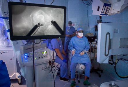 An operating room team performs a precision-guided procedure using real-time imaging displayed on a surgical monitor.