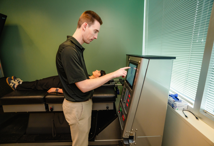 A student types on the machine's screen inputting patient information.