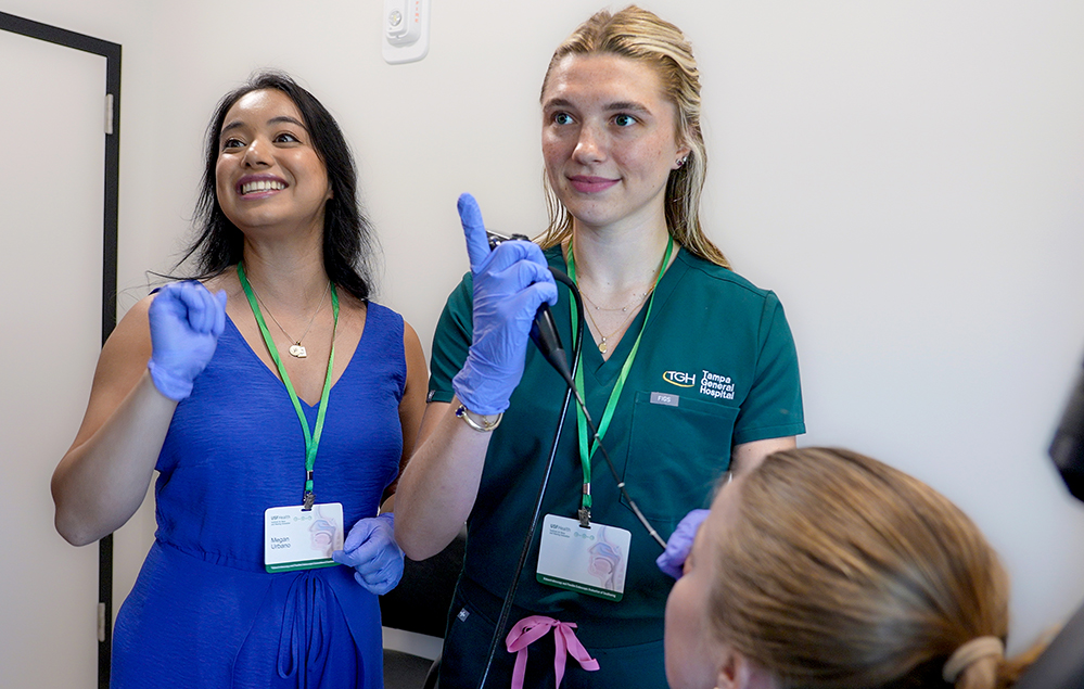 A student and a teacher scope a volunteer in an exam room. 