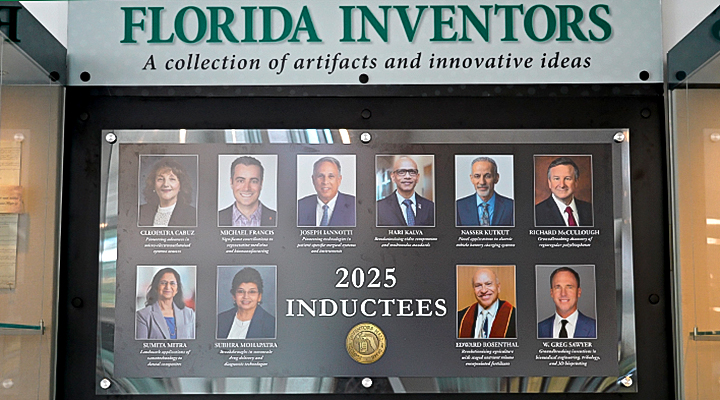Florida Inventors Hall of Fame display in the USF Connect building showing nine portrait photographs of 2025 inductees arranged around the text "2025 INDUCTEES" with a gold Hall of Fame seal. The display includes Dr. Michael Francis and other Florida innovators beneath a header reading "FLORIDA INVENTORS - A collection of artifacts and innovative ideas"