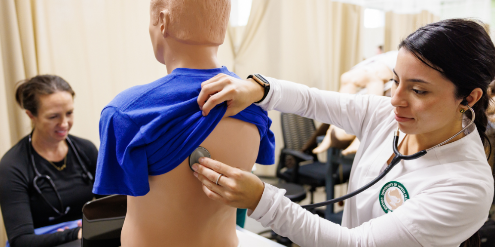 Nursing student listening to manikin's lungs